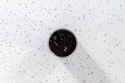 Flat lay. Opened a metal can with blueberry pie filling on the counter.