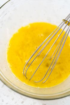 Mixing ingredients in a glass mixing bowl to prepare filling for breakfast empanadas with eggs and sweet potato.