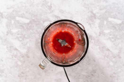 Flat lay. Blending fresh strawberries in a kitchen blender to prepare the strawberry buttercream frosting.