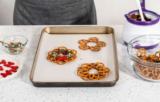Dipping pretzels twists into melted chocolate to make a chocolate pretzel Christmas wreath.