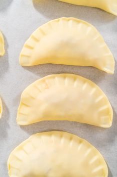 Brushing uncooked breakfast empanadas with eggs and sweet potato with egg wash.