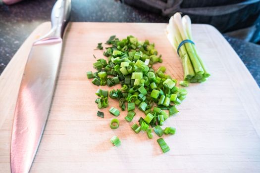 Cutting organic green onions on a wood cutting board.