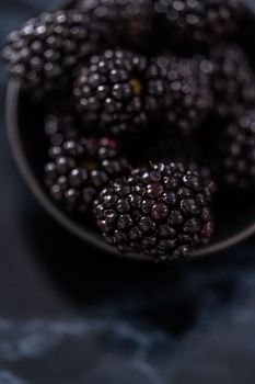 Fresh organic blackberries on ablack marble surface.