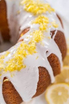 Lemon bundt cake decorated with lemon zest on a cake stand.