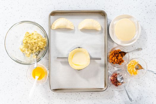 Flat lay. Filling empanada dough with egg filling to make breakfast empanadas with eggs and sweet potato.