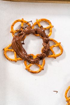 Dipping pretzels twists into melted chocolate to make a chocolate pretzel Christmas wreath.