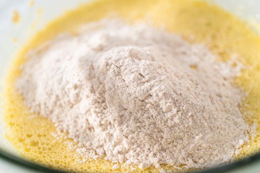 Mixing ingredients with a hand mixer in a large mixing bowl to bake eggnog bundt cake.