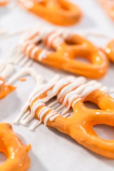 Drizzling melted chocolate over chocolate-dipped pretzels twists.