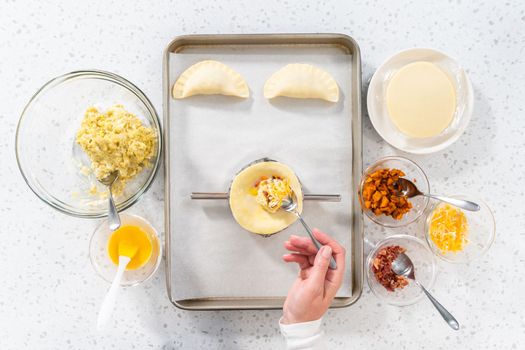 Flat lay. Filling empanada dough with egg filling to make breakfast empanadas with eggs and sweet potato.