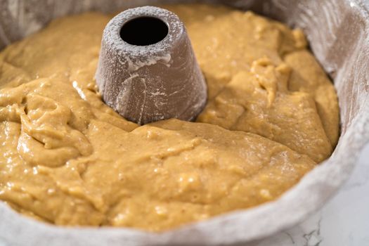 Filling metal bundt cake pan with cake butter to bake eggnog bundt cake with an eggnog glaze.