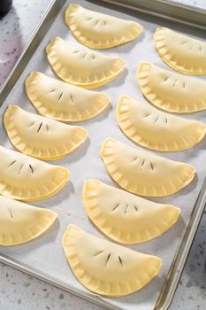 Brushing uncooked empanadas with blueberries with egg wash.
