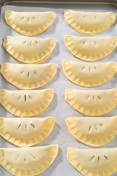 Brushing uncooked empanadas with blueberries with egg wash.