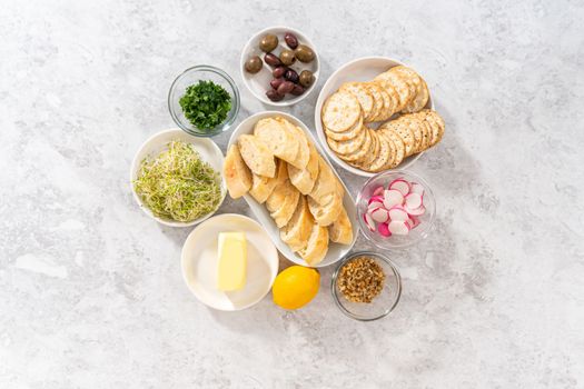 Flat lay. Measured ingredients in glass mixing bowls to make butter board with vegetables and bread.
