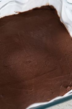 Removing plain homemade fudge from the baking pan lined with parchment.