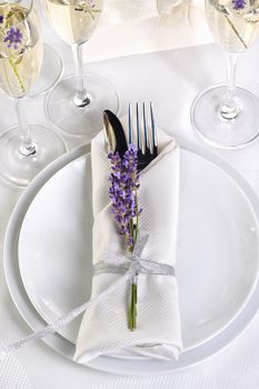 Dining table in Provence style, with Lavender Champagne, folded napkin with cutlery, decorated with fresh lavender. Detail of the wedding dinner. Wedding theme ideas.