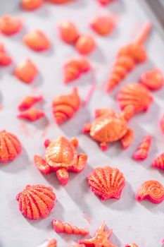 Painting sea-shaped chocolates with glittery luster to decorate chocolate-dipped pretzels twists.