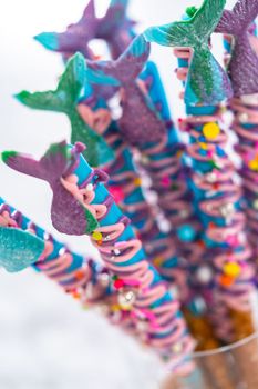 Mermaid chocolate pretzel rods drizzled with pink and purple chocolate and covered with sprinkles.