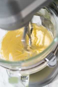 Mixing ingredients in kitchen electric mixer to make ombre pink buttercream frosting.