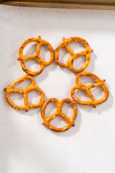 Dipping pretzels twists into melted chocolate to make a chocolate pretzel Christmas wreath.