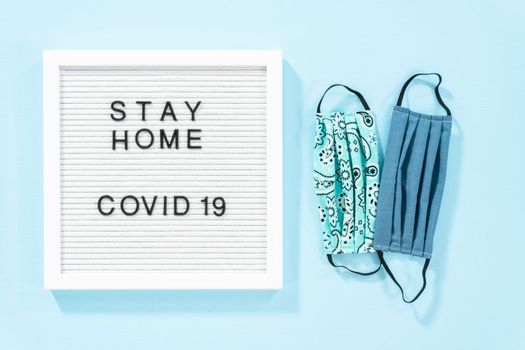 STAY HOME and COVID-19 sign on message board with a homemade face mask.