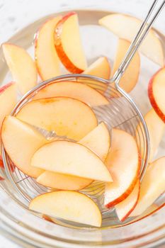 Washing apple slices in the water mixture to prevent them from browning.