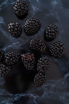 Fresh organic blackberries on ablack marble surface.