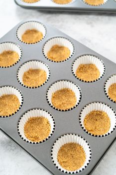 Filling cupcake liners with graham crackers to baking s'mores cupcakes.