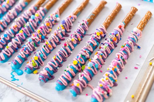 Mermaid chocolate pretzel rods drizzled with pink and purple chocolate and covered with sprinkles.