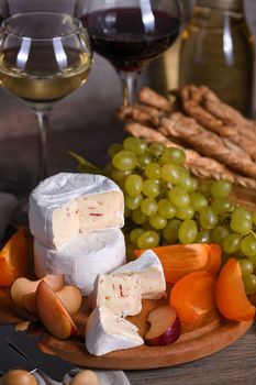 Cheese camembert with white grapes, sliced persimmons and plums, a great appetizer for wine 
