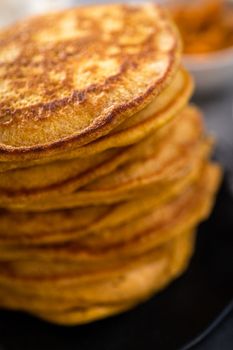 Stack of fresh pumpkin pancakes on a black plate.
