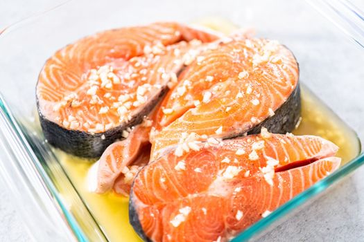 Marinating salmon steaks in a glass dish for grilling.