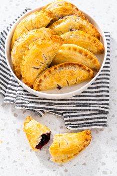Freshly baked sweet empanadas with blueberries on the kitchen counter.