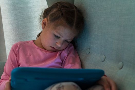 Little girl reading books on her tablet at homeschool.