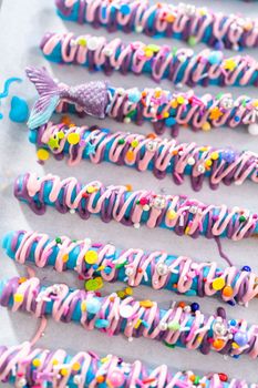 Mermaid chocolate pretzel rods drizzled with pink and purple chocolate and covered with sprinkles.