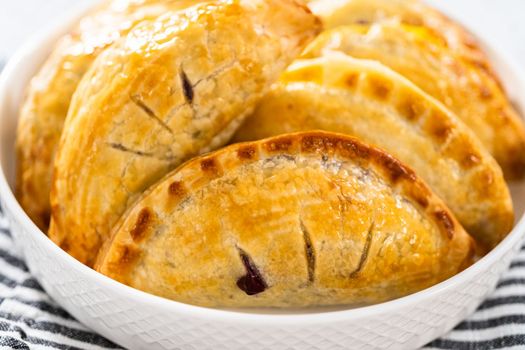 Freshly baked sweet empanadas with blueberries on the kitchen counter.