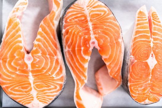 Farm-raised salmon steaks on a cooking tray with a parchment paper.