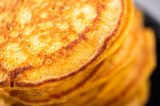 Stack of fresh pumpkin pancakes on a black plate.