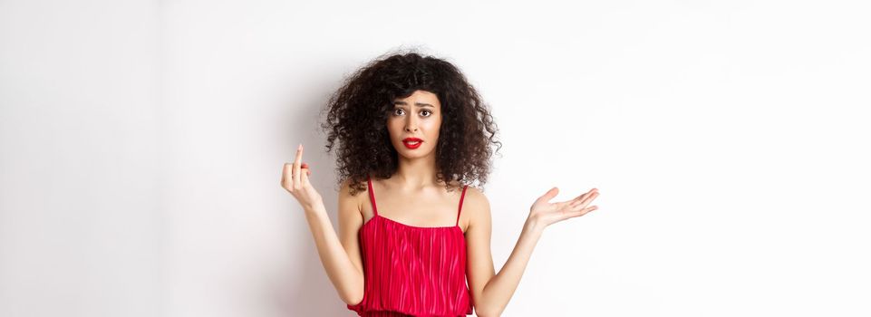 Annoyed caucasian woman in red dress, showing finger without wedding ring, arguing about marriage, standing pissed-off on white background.