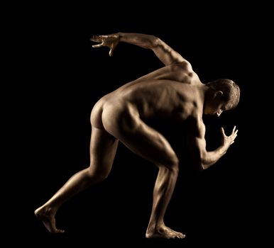 Athletic man posing nude in dark with metal skin