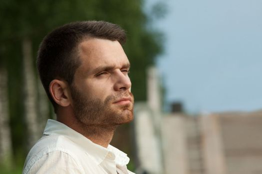 Sad young man portrait in summer park look at sunset