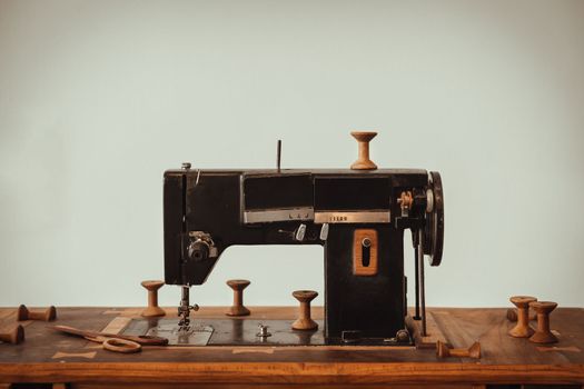 Old vintage sewing machine on wooden table on white wall background. Copy space, Selective focus.