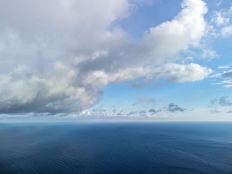 Blue sky with white clouds over calm summer panorama of the sea. Drone aerial view. Abstract aerial nature summer ocean sunset sea and sky background. Horizon. No people. Holiday and vacation concept