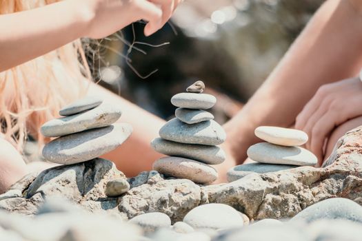 Balanced Pebbles Pyramid on the Beach on Sunny Day and Clear Sky at Sunset. Blue Sea on Background Selective focus, zen stones on sea beach, meditation, spa, harmony, calm, balance concept.