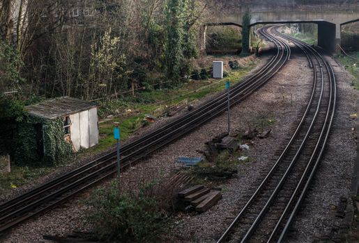 London, England - Mar 06, 2019 : Two old railway tracks stretching into passing under the bridge. Perspective of routes and railroad train tracks in london, No focus, specifically.