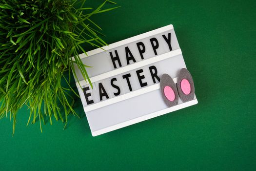 The inscription Happy Easter on the board on a green background. High quality photo