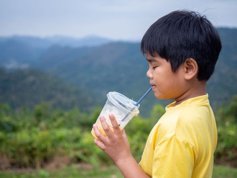 boy sucking a drink from a glass with a valley background