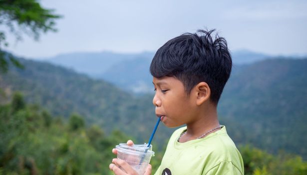 boy sucking a drink from a glass with a valley background