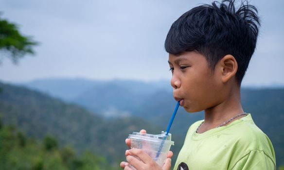 boy sucking a drink from a glass with a valley background