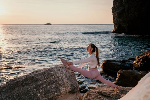 Young woman with black hair, fitness instructor in pink sports leggings and tops, doing pilates on yoga mat with magic pilates ring by the sea on the beach. Female fitness daily yoga concept