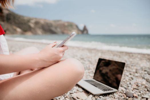 Woman sea laptop. Business woman in yellow hat working on laptop by sea. Close up on hands of pretty lady typing on computer outdoors summer day. Freelance, digital nomad, travel and holidays concept